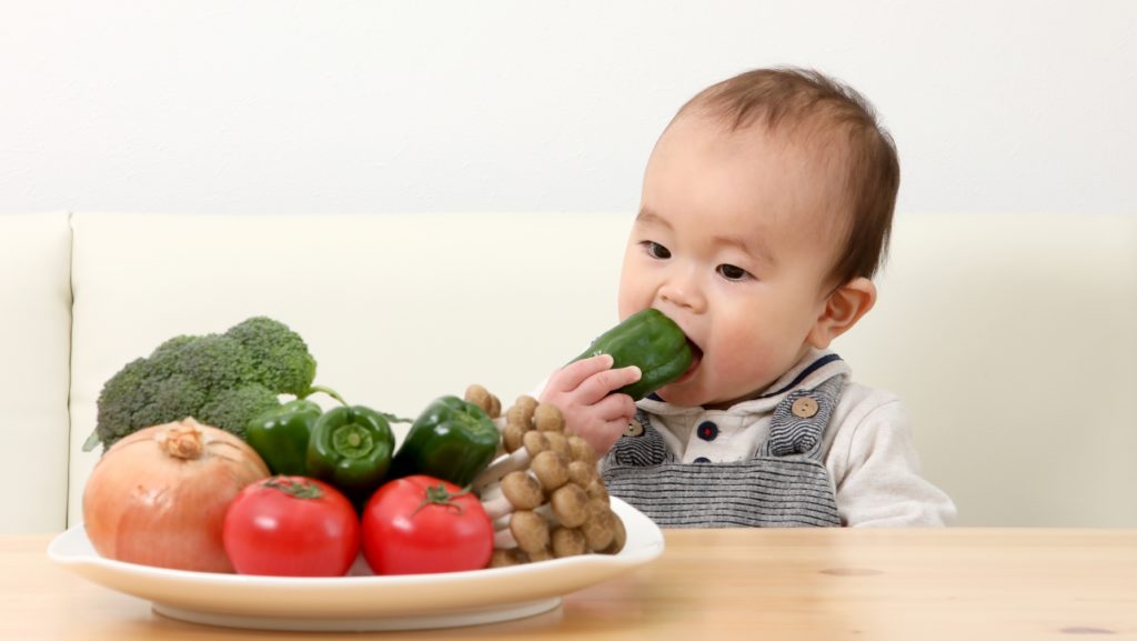 野菜をまるかじりしようとする赤ちゃんの写真