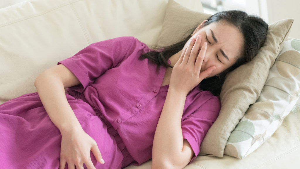 貧血による体調不良でソファーに寝ている妊婦さんの写真
