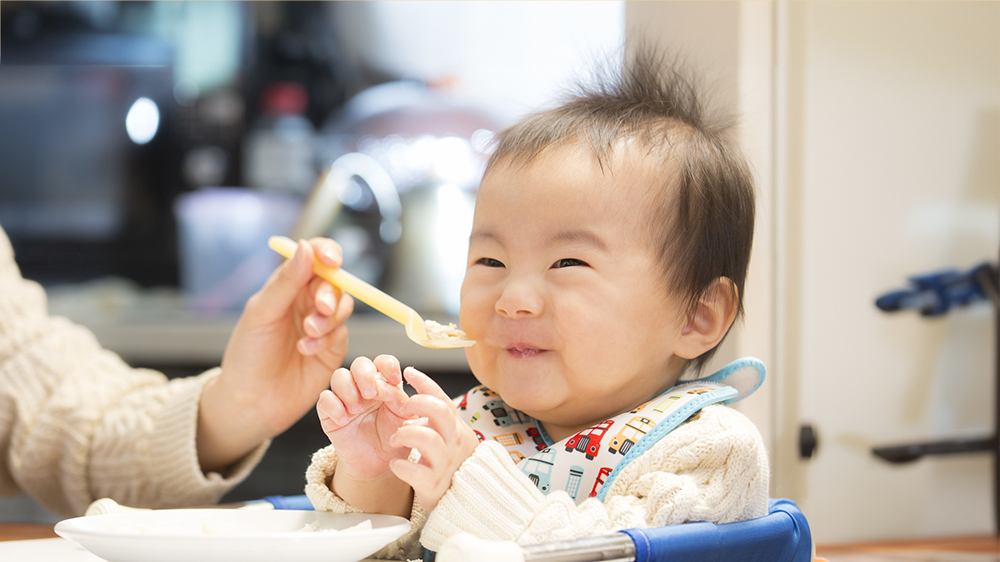 離乳食を笑顔で食べている赤ちゃんの写真