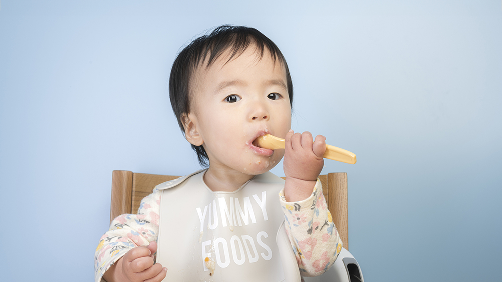 離乳食を自分で食べている子供の写真